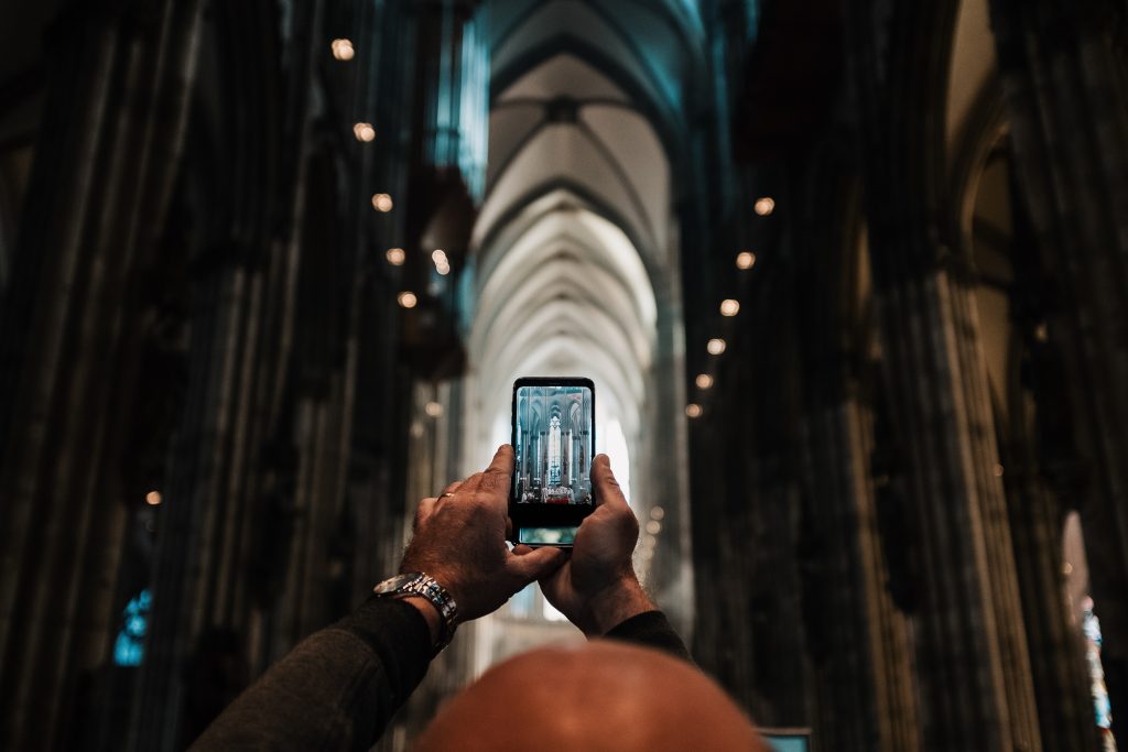 man-photographing-church-with-mobile-phone